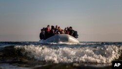 FILE - Refugees and migrants approach the Greek island of Lesbos on a dinghy after crossing the Aegean sea from the Turkish coast, on Monday, Dec. 7, 2015. 