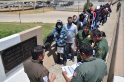 FILE - U.S. Border Patrol officers return a group of migrants back to the Mexico side of the border, as Mexican immigration officials check a list, in Nuevo Laredo, Mexico, July 25, 2019.