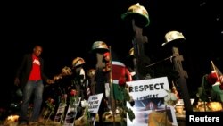 A volunteer arranges replicas of guns and helmets placed on the ground to symbolize Kenyan soldiers serving in the African Union Mission in Somalia (AMISOM) who were killed during an attack January 15, at a memorial vigil within the "Freedom Corner" in Ke