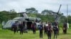 Hombres indígenas esperan para abordar un helicóptero en una base militar en Calamar, Colombia, el martes 23 de mayo de 2023, para ayudar en la búsqueda de cuatro niños desaparecidos después de un accidente aéreo. 