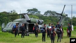 Hombres indígenas esperan para abordar un helicóptero en una base militar en Calamar, Colombia, el martes 23 de mayo de 2023, para ayudar en la búsqueda de cuatro niños desaparecidos después de un accidente aéreo. 