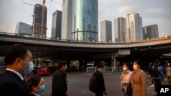 2020年4月17日戴口罩行人们穿过北京商业区一个十字路口。