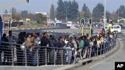 South African commuters line up at a bus stop in Soweto on 17 May 2010 during a strike by rail workers