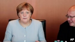 German Chancellor Angela Merkel, left, listens to chief of staff Peter Altmaier during a Cabinet meeting at the chancellery in Berlin, July 6, 2016.