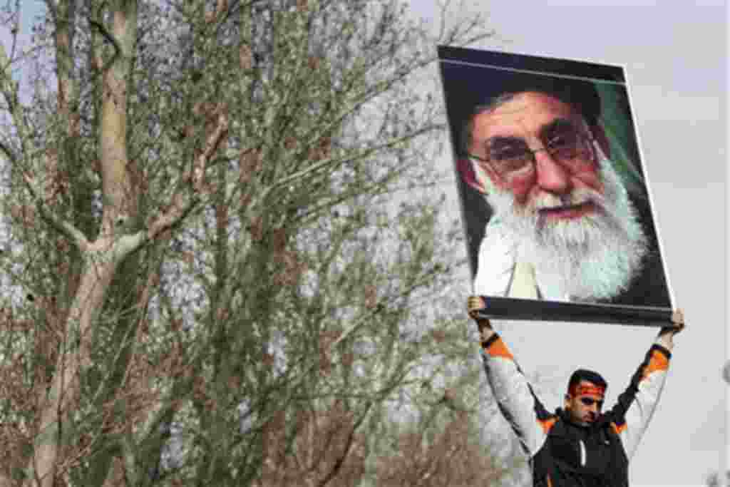 A pro-government Iranian holds a poster of supreme leader Ayatollah Ali Khamenei during the funeral ceremony of Sane Jaleh, a student who was killed during Monday's clashes, in Tehran, Iran, February 16, 2011