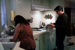 Kerry Osaki, right, helps his wife, Lena Adame, in the kitchen in their Fountain Valley, California, home, November 25, 2020. This year, their traditions have fallen to the pandemic that took the life of Osaki's 93-year-old mother.