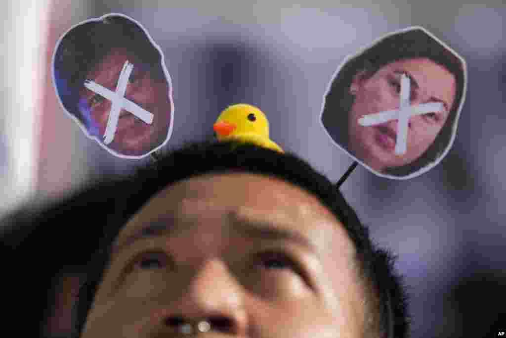 A protester looks at the crossed-out images of Philippine President Ferdinand Marcos Jr., left, and Vice-President Sara Duterte as he joins a protest&nbsp;against a plan by some lawmakers to change parts of the constitution, in Manila, Philippines.