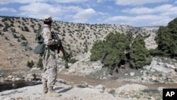 FILE - A Lebanon Hezbollah fighter carries his weapon as he stands in Khashaat, in the Qalamoun region, May 15, 2015. 