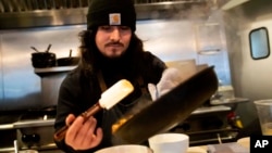 Santos Enrique Camara, 27, who dropped out of Shoreline Community College at age 19 in 2015, prepares food at Capers + Olives Friday, March 24, 2023, in Everett, Wash. (AP Photo/Lindsey Wasson)