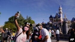 FILE - In this April 30, 2021, photo, a family takes a photo in front of Sleeping Beauty's Castle at Disneyland in Anaheim, Calif. 