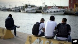 FILE - Unaccompanied minors from north Africa sit by the river Tiber, in Fiumicino, Italy, 30 kilometers (19 miles) west of Rome, April 21, 2016.