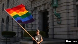 Bob Sodervick melambaikan bendera pelangi di luar pengadilan di San Francisco, California, menuntut pengakuan pernikahan sejenis (Foto: Dok)