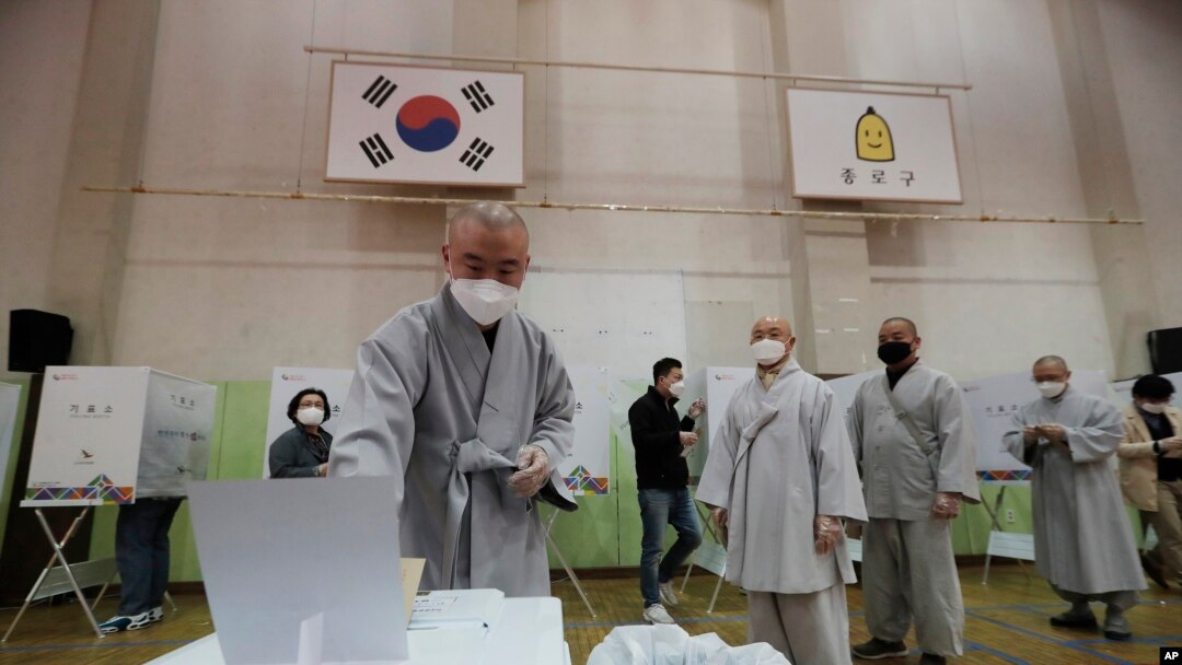 Seorang bhiksu mengenakan masker untuk melindungi dari penyebaran virus corona saat memberikan suaranya dalam pemilihan parlemen di i sebuah TPS di Seoul, Korea Selatan, Jumat, 10 April, 2020.