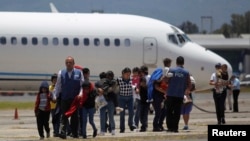 Des familles guatémaltèques déportées de Phœnix, à Arizona, marchent sur le tarmac après l’atterrissage de leur avion à l’aéroport de la ville de Guatemala, 22 juillet 2014.