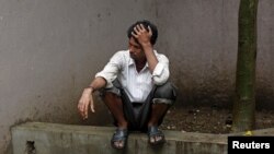 FILE - Indarlal waits to collect the body of his brother Rajesh, 30, who died after consuming bootleg liquor at a hospital in Mumbai, India, June 21, 2015. 