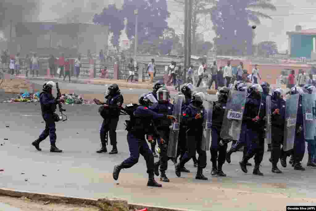 Um pol&#237;cia atira uma granada de fumo contra os manifestantes durante um protesto anti-governo em Luanda. A pol&#237;cia anti-motim, alguns montados em cavalos, disparou g&#225;s lacrimog&#233;neo e agrediu dezenas de manifestantes que tomaram as ruas da capital angolana