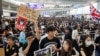 FILE - Anti-extradition bill protesters hold up placards for arriving travelers during a protest at the arrival hall of Hong Kong International Airport in Hong Kong, China, Aug. 9, 2019. 