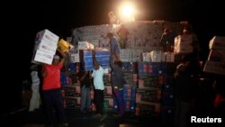Wayuu Indians carry boxes of goods from a cargo ship docked at a port in Pueblo Nuevo, Colombia, August 15, 2012. 