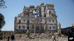 FILE - Houthi Shi'ite rebels walk amid the rubble of the Republican Palace that was destroyed by Saudi-led airstrikes, in Sana'a, Yemen, Dec. 6, 2017.