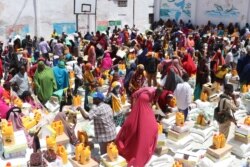 FILE - Internally displaced people gather to collect food rations being distributed to the families in the Shingani District of the Somali capital, Mogadishu, May 15, 2019.
