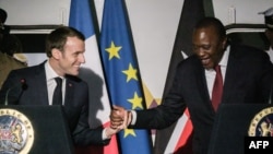 French President Emmanuel Macron, left, shakes hands with Kenyan President Uhuru Kenyatta during an event at Nairobi Central Railway Station in Nairobi, March 13, 2019, on the first day of a state visit to Kenya.