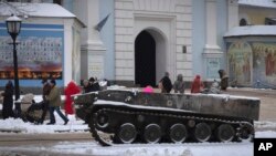 La gente pasa por la entrada de la Catedral de San Miguel, con un vehículo militar ruso dañado en primer plano, en el centro de Kiev, Ucrania, el lunes 12 de diciembre de 2022. (Foto AP/Efrem Lukatsky)