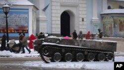 People pass by the entrance to St. Michael Cathedral, with a damaged Russian military vehicle in the foreground, in central Kyiv, Ukraine, Dec. 12, 2022. 