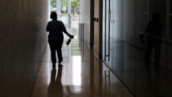 A worker from Boston University's maintenance department carries a bottle of sanitizer, due to concerns over the COVID-19 virus outbreak, while making her cleaning rounds at a campus building, Thursday, July 23, 2020, in Boston.