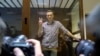 Russian opposition leader Alexey Navalny gestures as he posed for photographers standing in a glass enclosure at the Babuskinsky District Court in Moscow, Russia, Feb. 20, 2021. 