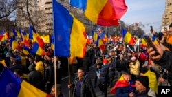 Protesters walk holding Romanian flags during a rally calling for free elections after Romania' s Constitutional Court annulled the first round of presidential elections, in Bucharest, Jan.12, 2025. 