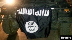 FILE - The Islamic State flag is displayed during celebrations in Mosul, Iraq.