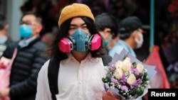 A man wears a gas mask as he holds a bouquet of flowers, following the outbreak of the novel coronavirus on Valentine’s Day in Hong Kong, China, Feb. 14, 2020.