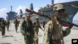 Somali National Army soldiers and pro-government Ras Kamboni brigadiers walk along seaport quay, Kismayo, Nov. 2, 2012.