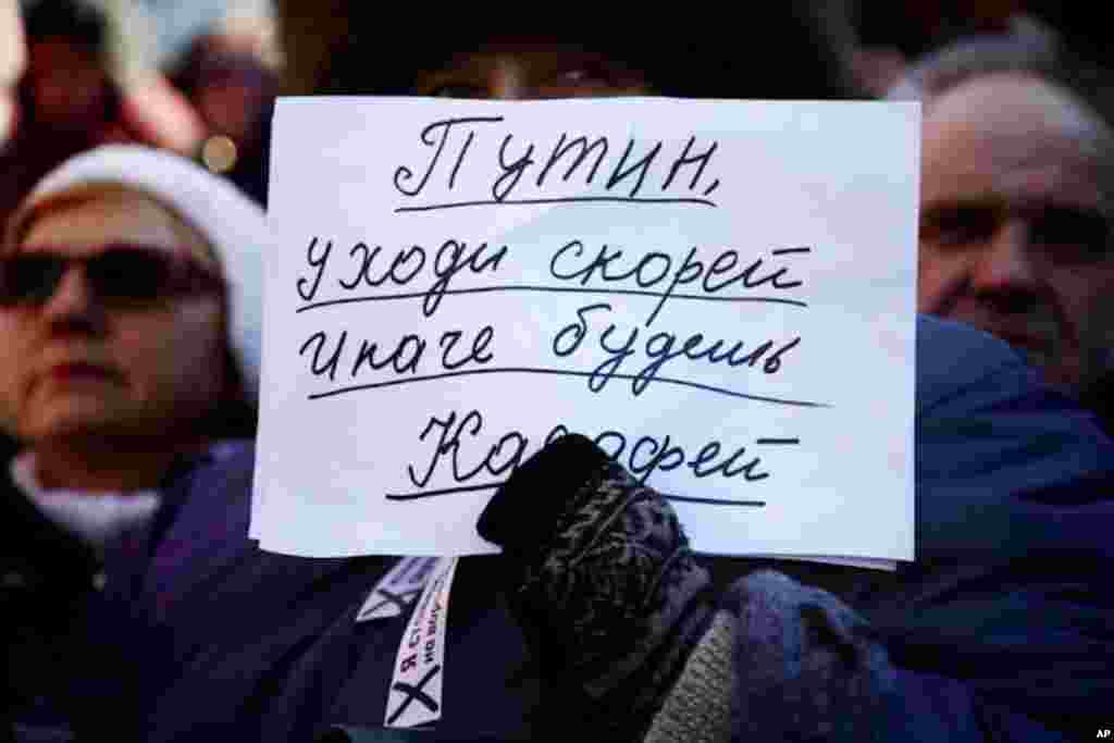 A protester holds a sign that reads, "Putin, leave soon or else you'll end up like Ghadafi." (VOA Photo - Yuli Weeks)