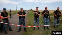 Separatistas prorrusos armados montan guardia en el sitio en que cayó el avión MH17.