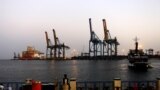 FILE - A man stands opposite the modern port at the harbor in Port Sudan at the Red Sea state, Feb. 24, 2014. 