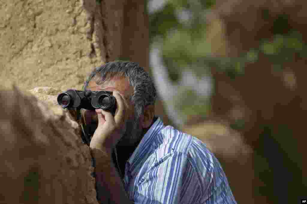 Un Turc Kurde regarde à travers des jumelles à Mursitpinar, dans les périphéries de Suruc, à la frontière Turco-Syrienne alors que des combats font rage entre les combattants de l&rsquo;Etat islamique et les forces kurdes à Kobani, en Syrie, le 12 octobre 2014. (AP Photo/Lefteris Pitarakis) 