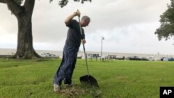 Richard Whitlock menyapu daun-daun dan sisa sampah di halaman depan rumahnya yang menghadap Teluk Meksiko menyusul Badai Tropis Gordon, 5 September 2018.