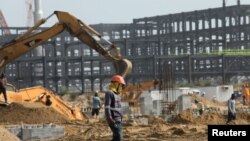 A worker walks past excavators at a construction site of the Dangote refinery in Ibeju Lekki district, on the outskirts of Lagos, Nigeria, August 7, 2019. 