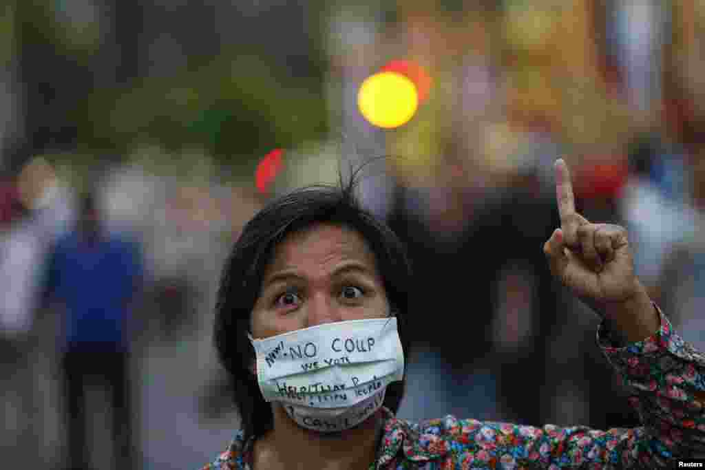 A protester against military rule with messages written on her face mask gestures as protesters gather at the Victory Monument in Bangkok, May 26, 2014.