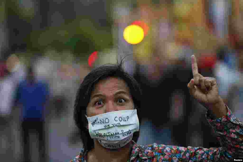 Seorang demonstran memakai masket bertuliskan pesan anti-kudeta dalam sebuah protes di Monumen Kemenangan di Bangkok (26/5).