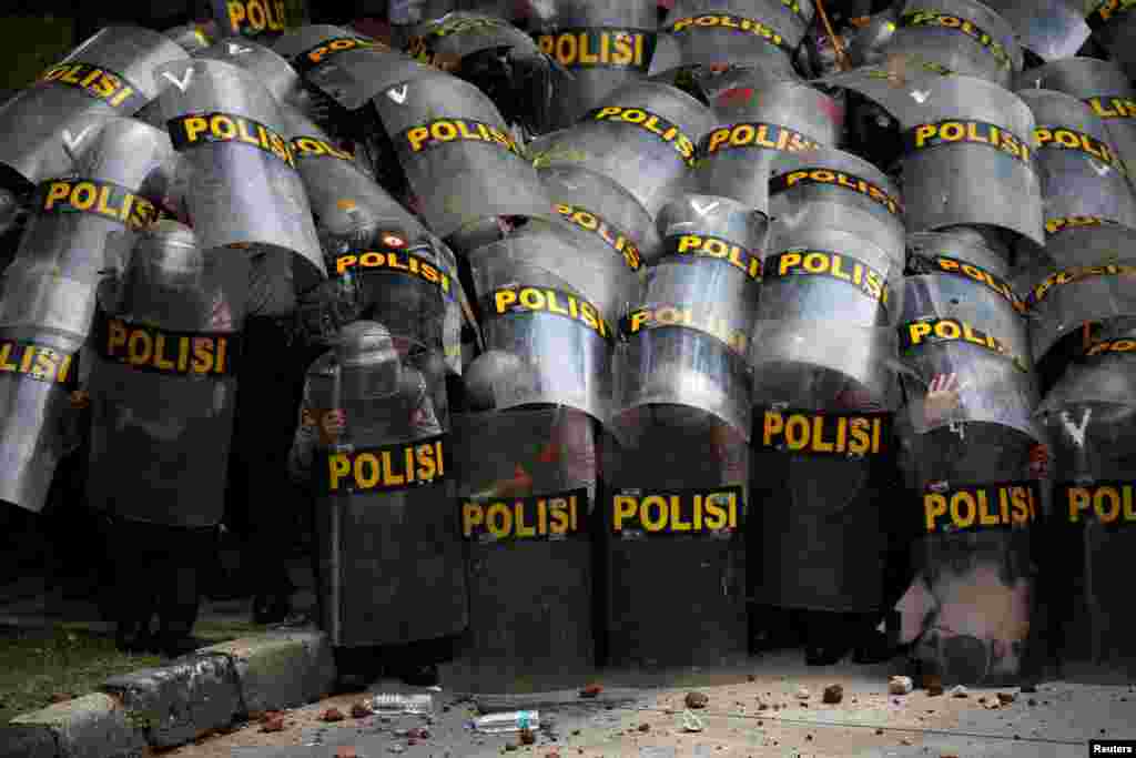 Police officers protect themselves with their shields during a protest against the new so-called omnibus law, in Jakarta, Indonesia.