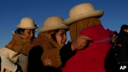 Las mujeres aymaras se abrazan después de recibir los primeros rayos de sol en un ritual de Año Nuevo en la montaña sagrada Apacheta Murmutani en las afueras de Hampaturi, Bolivia.