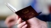 FILE - A police officer checks the passport of a Chinese immigrant in Prato, Italy, Dec. 9, 2013. 