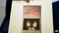 FILE - A city employee sets up a display board in preparation for a news conference regarding human traffickers in Long Beach, Calif., Sept. 24, 2014.