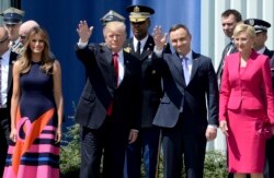 U.S. President Donald Trump, left, waves along with Poland's President Andrzej Duda, as U.S. First Lady Melania Trump, left and Poland's first lady Agata Kornhauser-Duda, right, stand by, in Krasinski Square, in Warsaw, Poland, July 6, 2017.