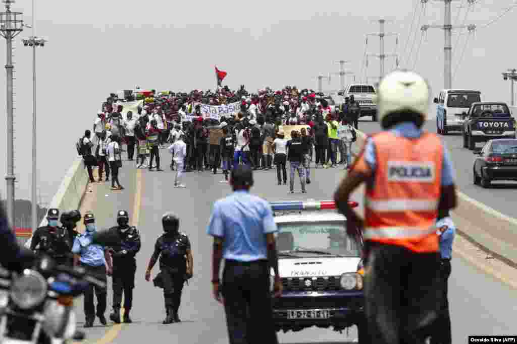 A pol&#237;cia observa as pessoas a reunirem-se durante a manifesta&#231;&#227;o para protestar contra o aumento do custo de vida, a corrup&#231;&#227;o em todo o pa&#237;s e para exigir a realiza&#231;&#227;o de elei&#231;&#245;es locais, em Luanda, a 20 de Mar&#231;o de 2021.