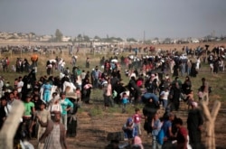 FILE - In this June 14, 2015 file photo taken from the Turkish side of the border between Turkey and Syria, in Akcakale, Sanliurfa province, southeastern Turkey, thousands of Syrian refugees walk in order to cross into Turkey.