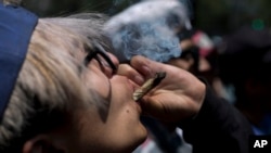 FILE - A young man smokes marijuana to celebrate the International Day for Cannabis in Mexico City, April 20, 2018. 
