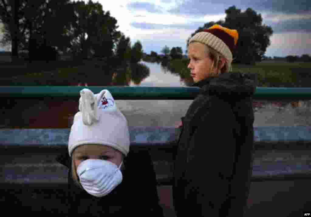 Children stand on a bridge over the River Marcal containing the toxic red sludge that spilled Monday from a giant industrial container near Mersevat, Hungary, Thursday, Oct. 7, 2010. "Life in the River Marcal has been extinguished," Rescue official Tibor 